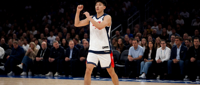 NBA球员在跳球前于球场热身，背景可见观众席人群